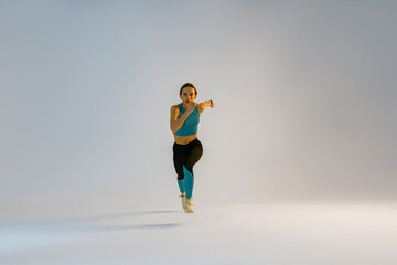 Woman running during cardio workout over studio background. High quality photo