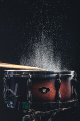 Fototapeta na wymiar Drummer using drum sticks hitting snare drum with splashing water.