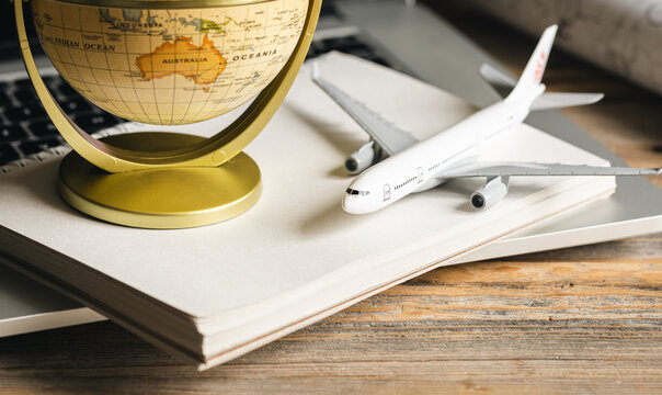 Travel composition with a model of an airplane and a globe on a wooden table. - Powered by Adobe