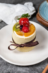 Fruit cream cake. Strawberry, pear, kiwi and raspberry cake covered with white chocolate on a dark background. Patisserie desserts