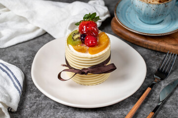 Fruit cream cake. Strawberry, pear, kiwi and raspberry cake covered with white chocolate on a dark background. Patisserie desserts