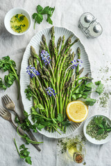 Green asparagus in plate with cooking ingredients, top view
