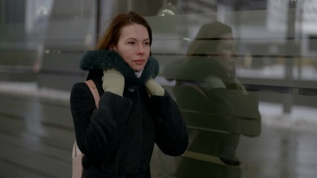 depressive middle-aged woman walking down street in city in winter day, medium portrait