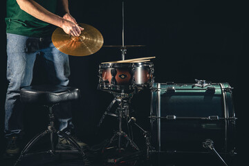 A man is a drummer and a drum set, the musician is preparing to play.