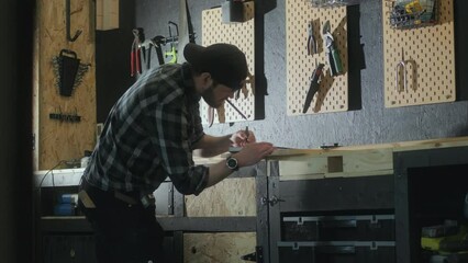 Young carpenter working on wood project at his studio, side view
