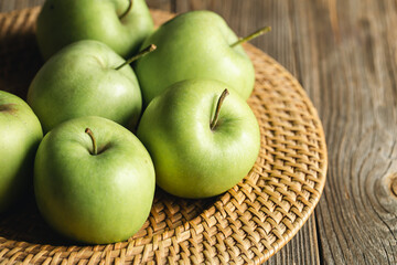 Close-up, green apples in a straw plate close-up.