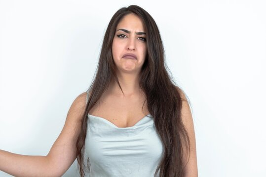 young brunette woman wearing white tank top over white studio background depressed and worry for distress, crying angry and afraid. Sad expression.