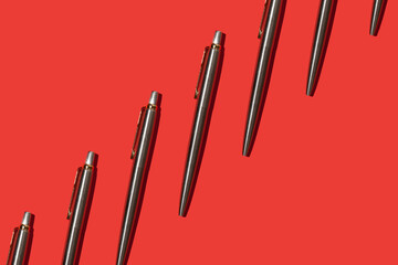 metal ballpoint pens on red background pattern