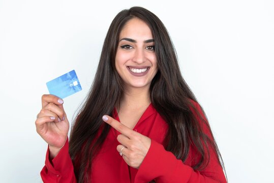 Photo portrait of Young brunette woman wearing red shirt over white studio background doing purchase with pointing finger credit bank card