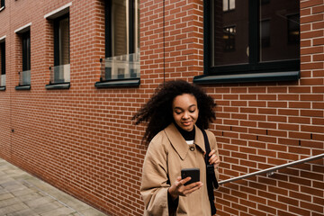 African girl using smartphone while walking outdoors