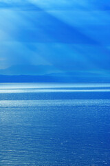 Obraz premium Morning sunlight beaming through clouds at Kvarner gulf of Adriatic sea in Croatia