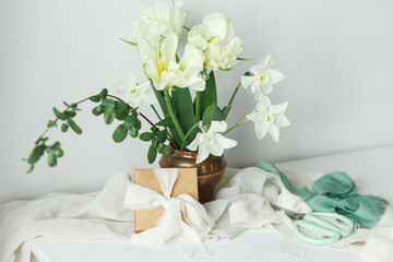 Happy Mothers day. Beautiful white bouquet with gift box on wooden table against rustic wall....