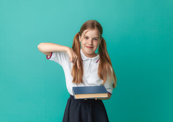 Smiling little blonde girl 10-12 years old in school uniform with backpack holding books isolated on pastel blue background studio portrait. The concept of children's lifestyle. Education at school.