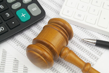 Financial fraud concept. Pen and wooden judge gavel with two calculators on financial documents.