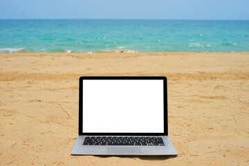 Laptop with blank screen for creative design on sand beach nearby blue sea background. Computer notebook with monitor clipping path for present landing page design mock up template