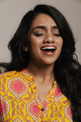 Portrait of indian woman singing while standing isolated over grey background