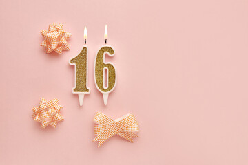 Number 16 on a pastel pink background with festive decorations. Happy birthday candles. The concept...