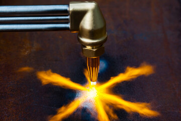 Gas cutting of metal. Gas cutter with copper nozzle with a stream of fire directed at the metal....