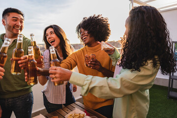 group of friends partying with beer on rooftop - multiracial women toast with beer.