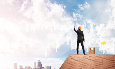 Man architect draw silhouette of modern city on blue sky. Mixed media