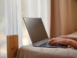 Fototapeta premium Happy young asian woman with laptop resting in bedroom in tiny house, weekend away and remote office idea. Tiny houses and Small Living concept.