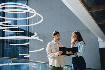 Two business people reading a financial report together in a conference center