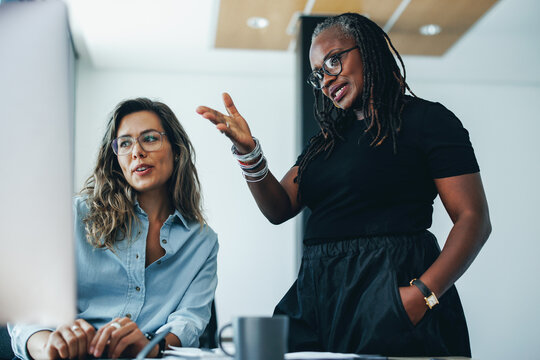 Mature black business woman having a discussion with her colleague in front of a computer