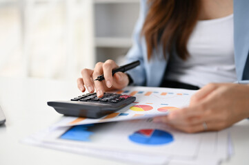 Fototapeta premium Close-up image of a female accountant using calculator and examining financial report