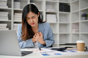 Unwell Asian businesswoman feeling chest pain, suffering from heart attack during work