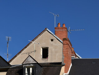Blue sky and house roof with chimneys and television antenna