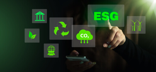 Woman using smartphone and touching ESG icon concept in the hand for environmental, social, and...