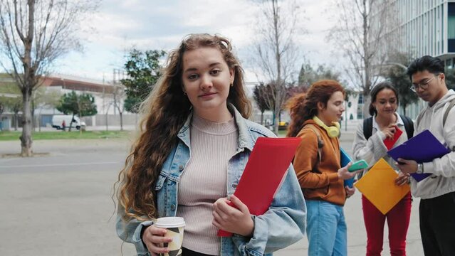 Portrait of Blond girl Student Woman wearing denim jacket holding red folder and notebooks outside the University