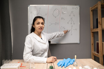Chemistry teacher having online class and showing molecular model on whiteboard, looking at camera....