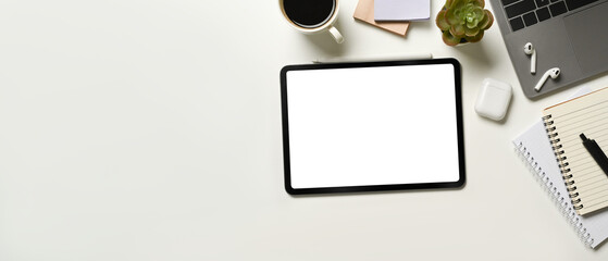 Digital tablet on white office desk table notebook, laptop and other office supplies. Top view with copy space.