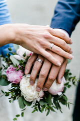 Obraz na płótnie Canvas Hände eines Brautpaars auf Brautstrauß mit Eheringen