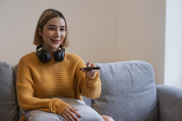 Asian young beautiful woman watching fun movie on television at home. Attractive casual girl feel happy and relax, sit on sofa having fun watch comedy video on TV in house. Activity lifestyles concept