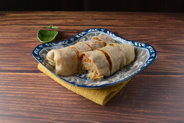 traditional peranakan nonya popiah healthy spring roll wrap with mixed vegetables and sweet sauce on chinese old retro plate and chopstick on wood table halal local vegan food appetiser snack menu