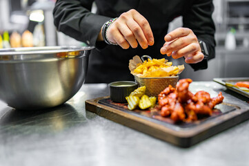 chef cookind chicken breast strips and french fries on restaurant kitchen