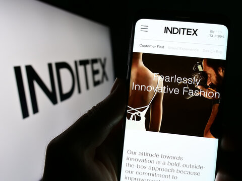 Stuttgart, Germany - 04-16-2023: Person holding cellphone with webpage of Industria de Diseno Textil S.A. (Inditex) on screen in front of logo. Focus on center of phone display.