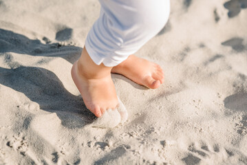 Baby feet barefoot walking on the sand on the sandy beach. Girl legs toddler. Top view, flat lay....