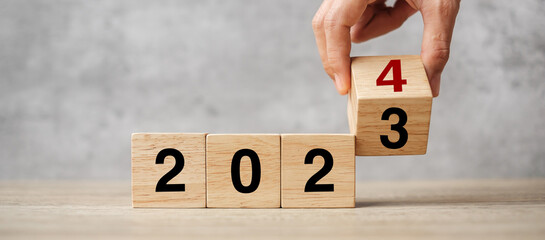 hand flipping block 2023 to 2024 text on table. Resolution, strategy, plan, goal, motivation,...