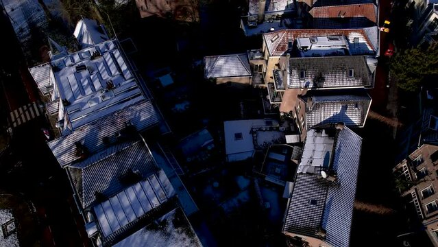 Top down winter wonderland rooftops covered in snow with aerial reveal of Drogenapstoren and historic Hanseatic Dutch tower town Zutphen in The Netherlands with Walburgiskerk cathedral in the back