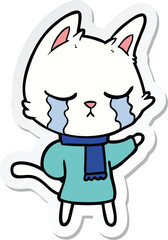 sticker of a crying cartoon cat wearing winter clothes