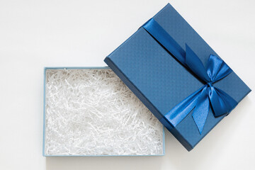 Open gift box with shredded paper on a white background. Blue cardboard box with decorative fillers...