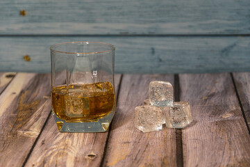 front view of a glass of whiskey with ice on a wooden background with space for writing
