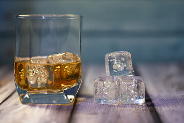 

front view of a glass of whiskey with ice on a wooden background with space for writing