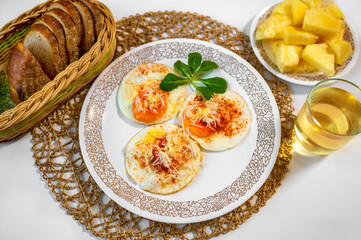 Fried egg with horseradish, bread, drink and sliced pineapple on white .