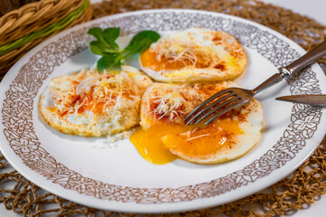 Fried egg with horseradish, leaf on plate, yolk melts under fork