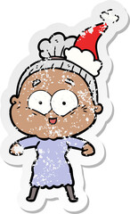 hand drawn distressed sticker cartoon of a happy old woman wearing santa hat