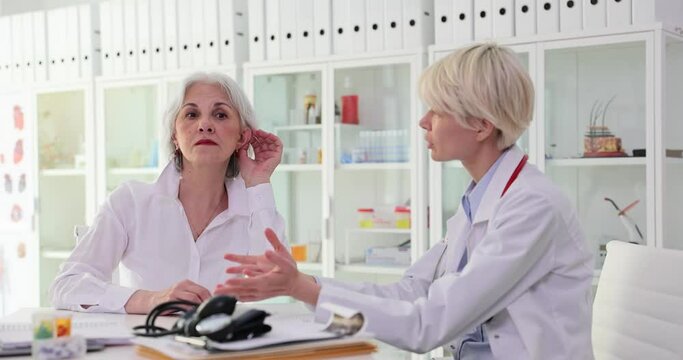 Otolaryngologist checks ear of mature woman with hearing problem. Hearing test for elderly